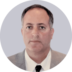 A headshot of Mr. Adam Emanuel, a middle-aged man with a neutral expression wearing a suit and tie.